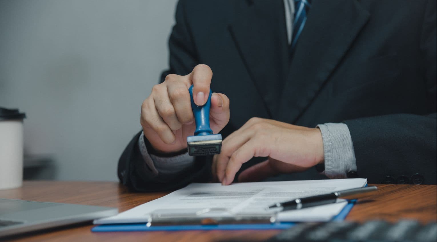 man's hand holding stamp over papers at bank